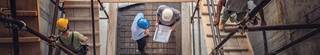 Top-down view of construction workers walking up wood ramps at a building site