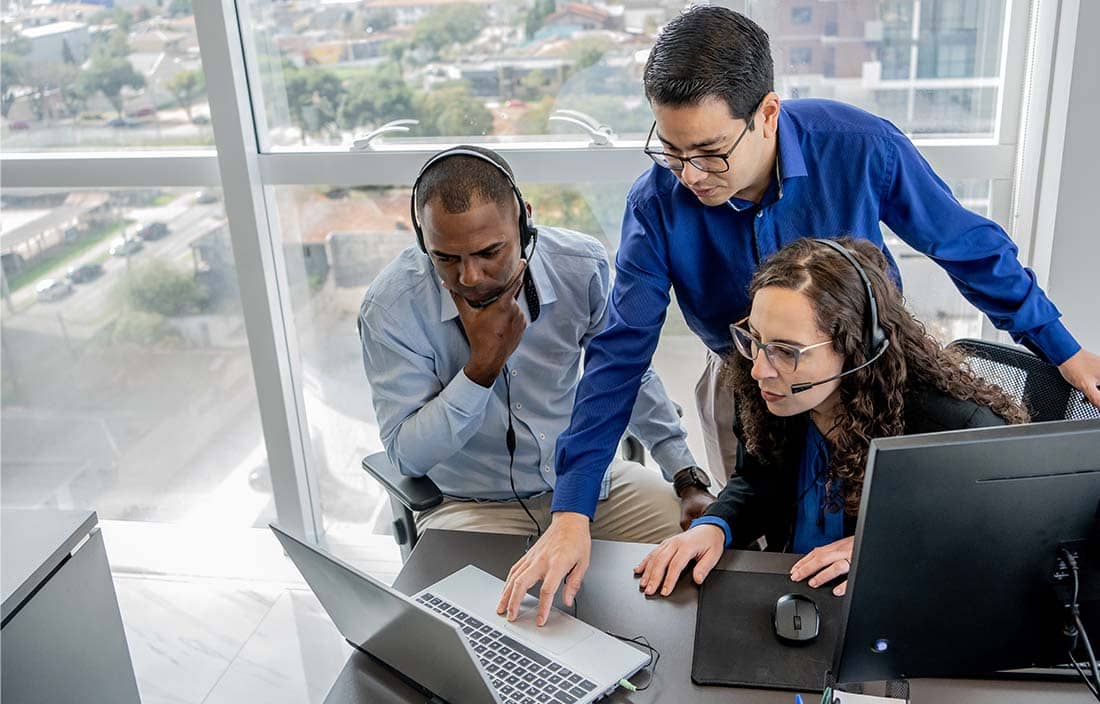 Group of cybersecurity professionals gathered around a computer.