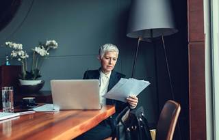 Person looking at work documents and their computer.