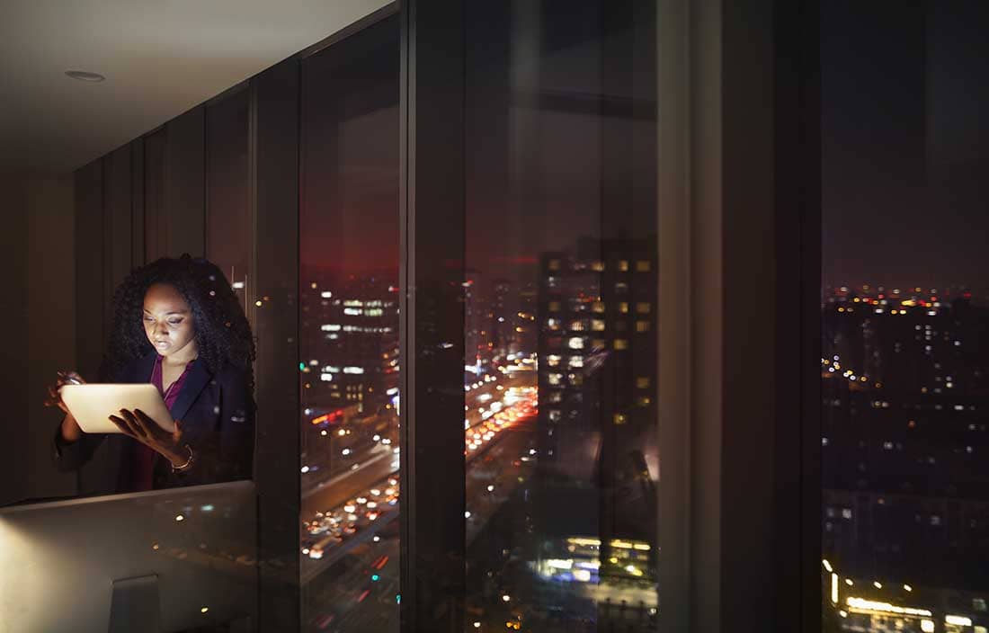 Business professional looking at tablet computer at nighttime.