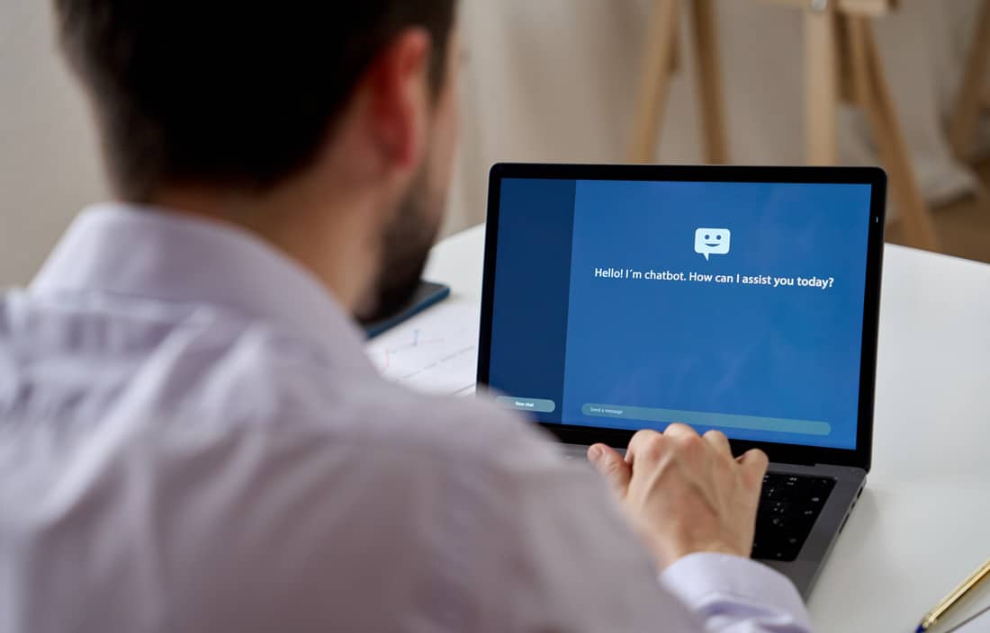 Business professional talking to an AI chatbot on their laptop.