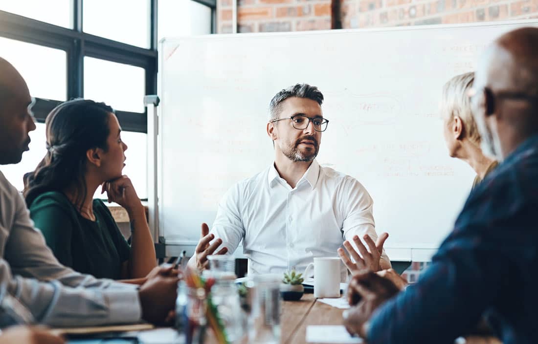Business professionals sitting at a table discussing turning experience into sustainable performance