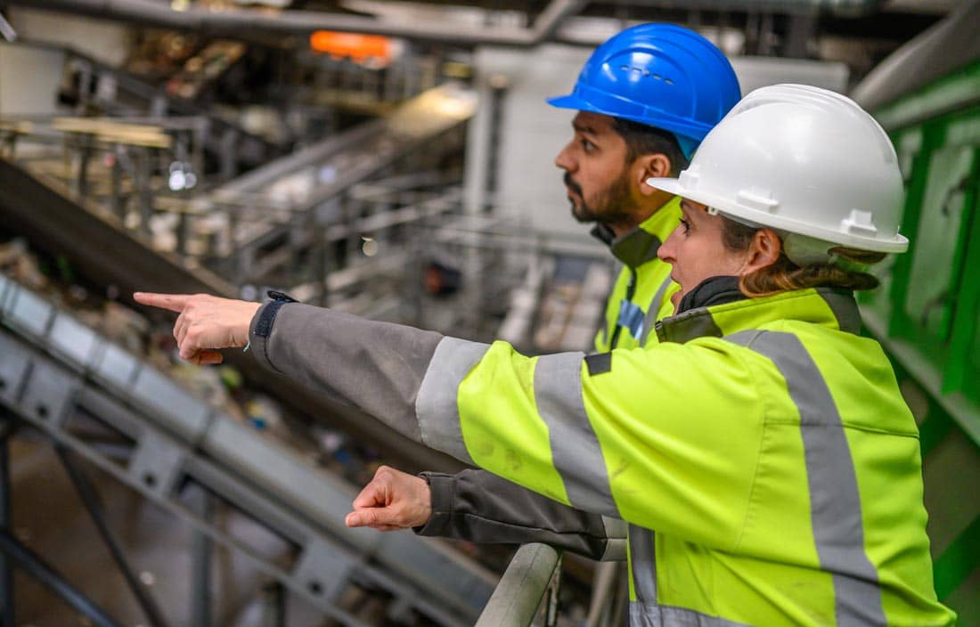 Two people in high-vis jackets and hard hats talking.