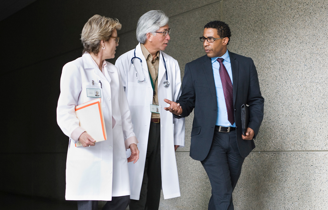 Business professional walking alongside two doctors.