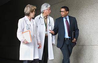 Business professional walking alongside two doctors.