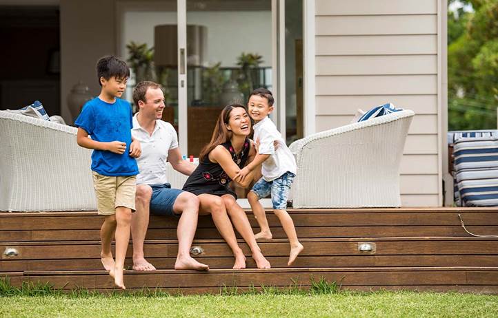 Wealthy parents playing with their two kids on their front lawn.