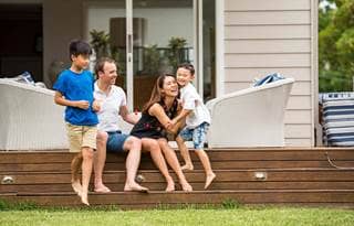 Wealthy parents playing with their two kids on their front lawn.