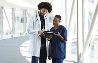 Doctors reviewing their medical charts in a hospital hallway.