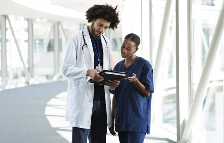 Doctors reviewing their medical charts in a hospital hallway.
