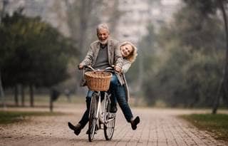 Happy mature couple having fun on a bicycle in autumn day