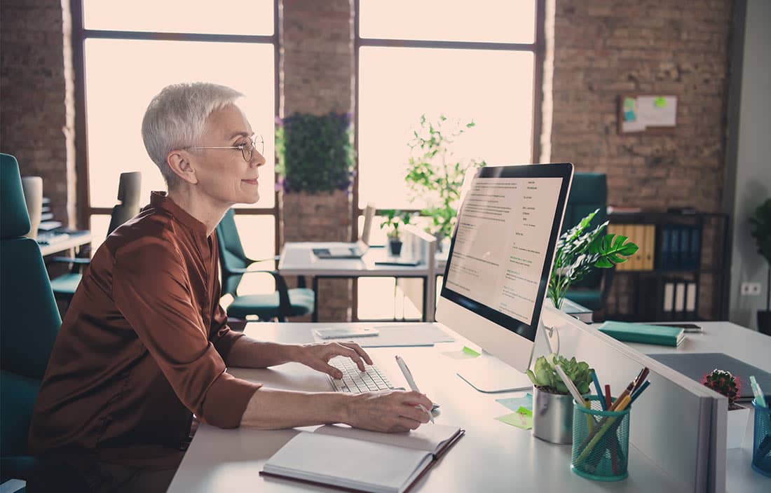 Professional real estate consultant, an older lady, sitting at a computer in an office