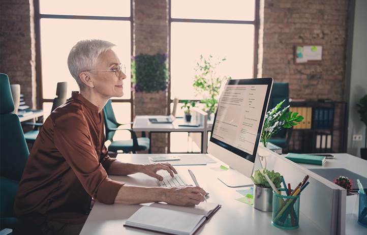 Professional real estate consultant, an older lady, sitting at a computer in an office