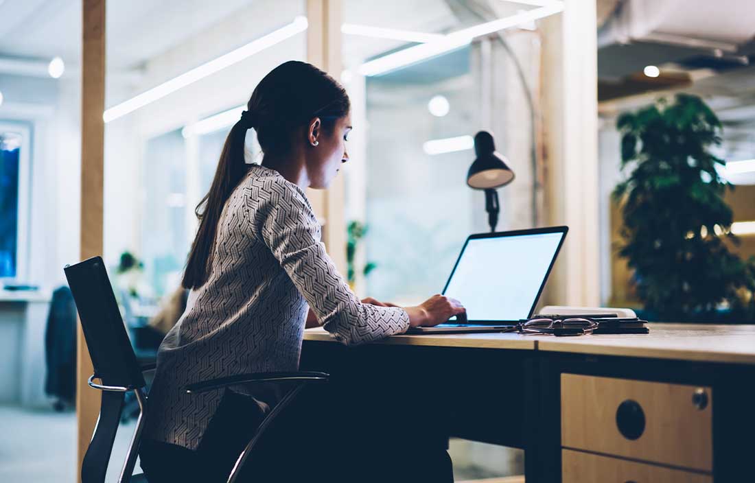 Woman sitting at a desk looking at a computer screen.
