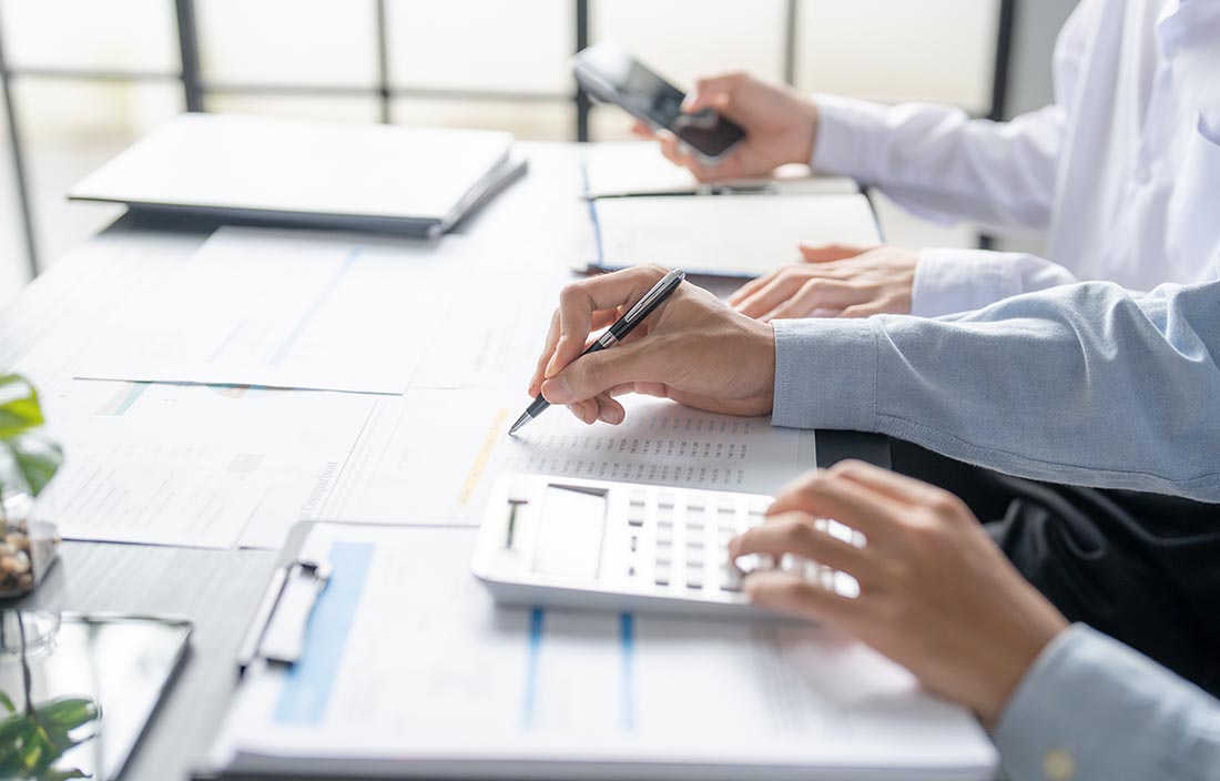 Person writing at a desk with papers on the table.