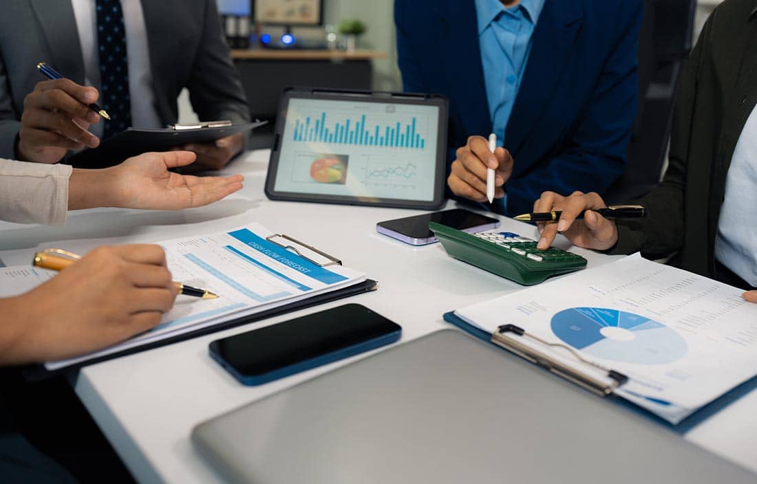 People looking at charts and graphs on paper and a tablet.