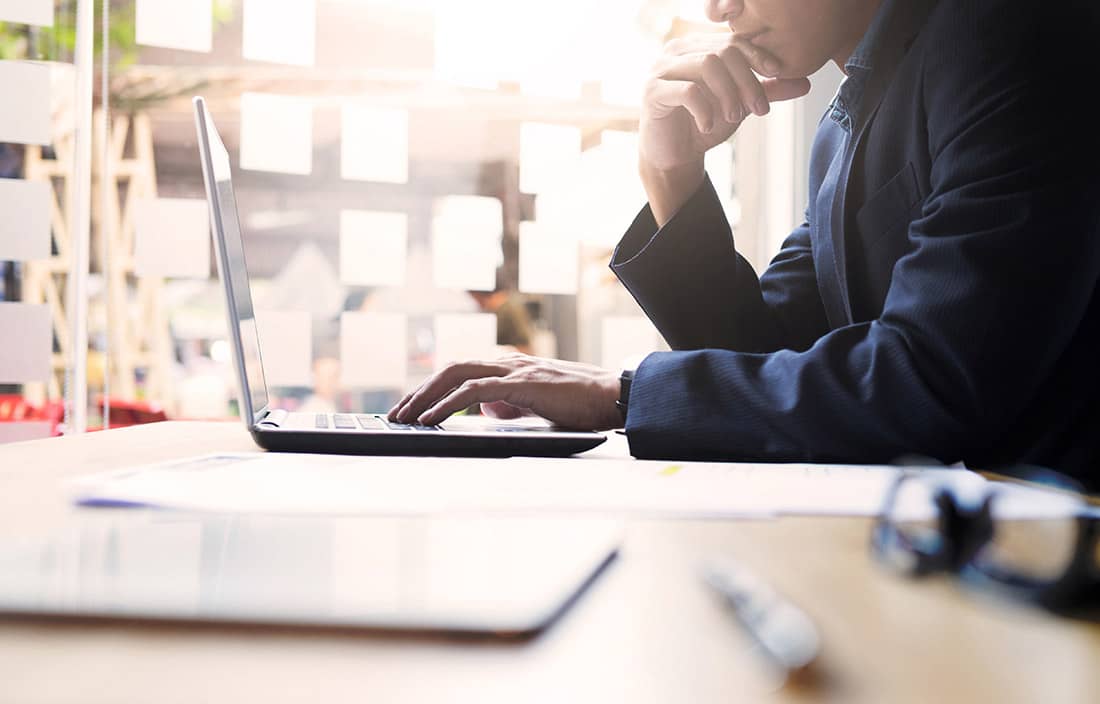 Image of a man at a desk looking at a laptop.
